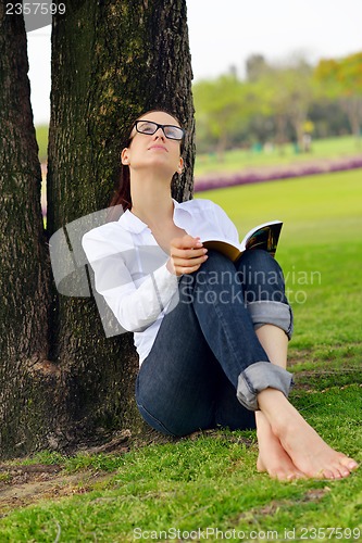 Image of Young woman reading a book in the park