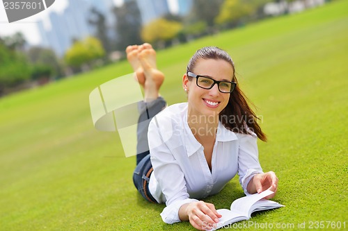 Image of Young woman reading a book in the park