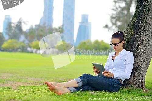 Image of Beautiful young woman with  tablet in park