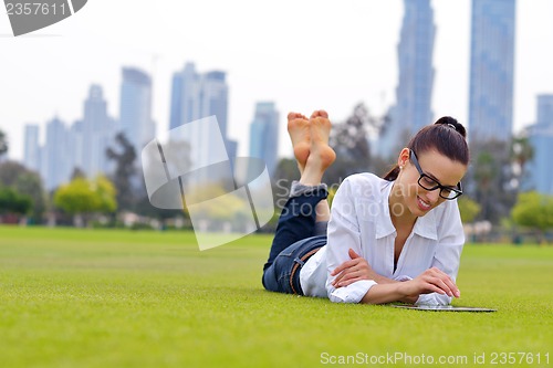 Image of Beautiful young woman with  tablet in park