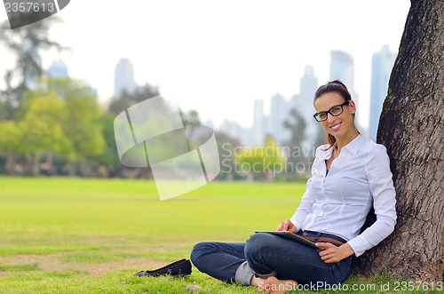 Image of Beautiful young woman with  tablet in park