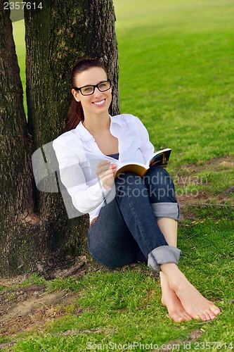 Image of Young woman reading a book in the park