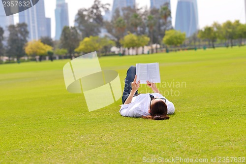 Image of Young woman reading a book in the park