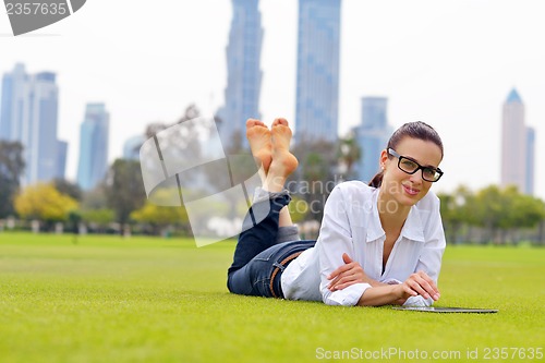 Image of Beautiful young woman with  tablet in park