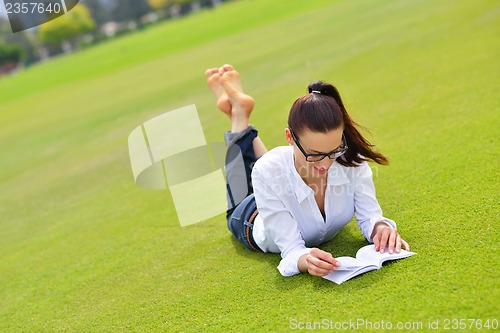 Image of Young woman reading a book in the park