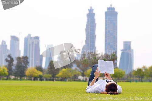 Image of Young woman reading a book in the park