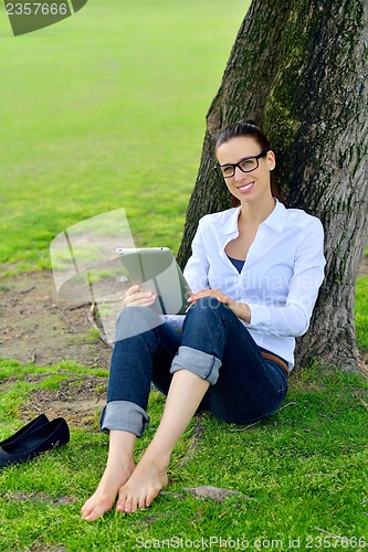 Image of Beautiful young woman with  tablet in park