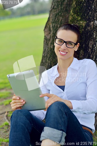 Image of Beautiful young woman with  tablet in park