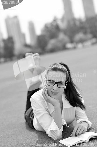 Image of Young woman reading a book in the park