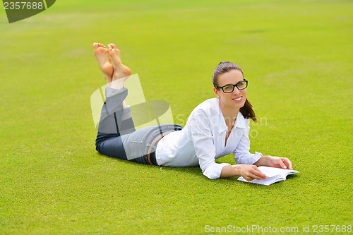 Image of Young woman reading a book in the park