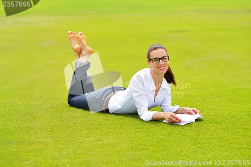 Image of Young woman reading a book in the park