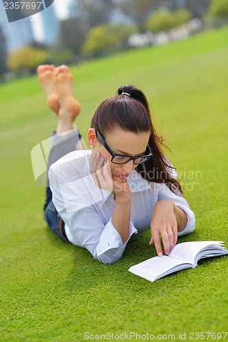 Image of Young woman reading a book in the park