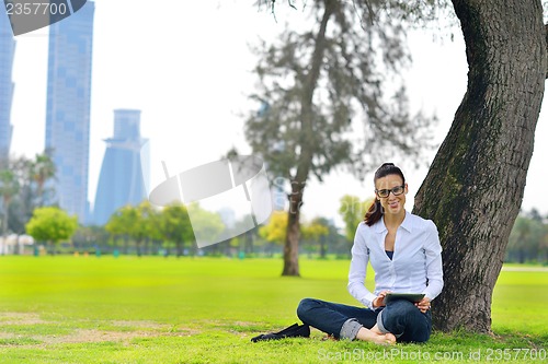 Image of Beautiful young woman with  tablet in park