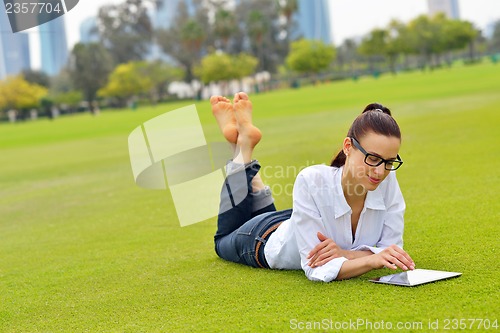 Image of Beautiful young woman with  tablet in park