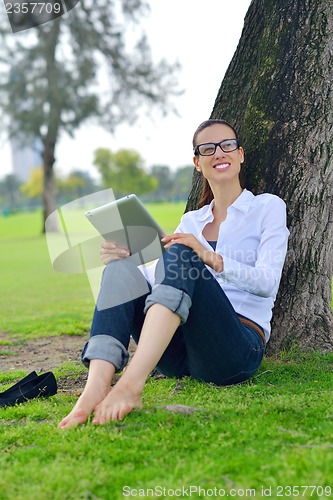Image of Beautiful young woman with  tablet in park