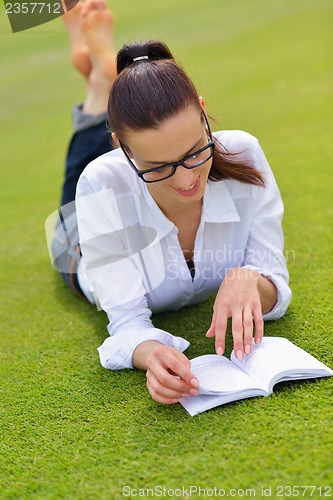 Image of Young woman reading a book in the park