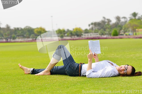 Image of Young woman reading a book in the park