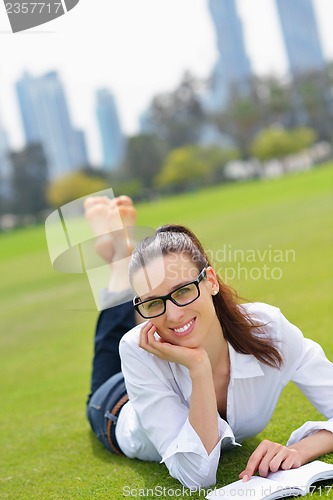 Image of Young woman reading a book in the park