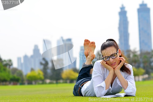 Image of Young woman reading a book in the park