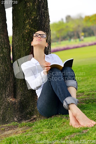 Image of Young woman reading a book in the park