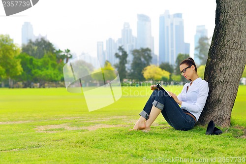 Image of Young woman reading a book in the park