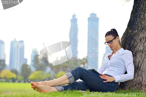 Image of Beautiful young woman with  tablet in park