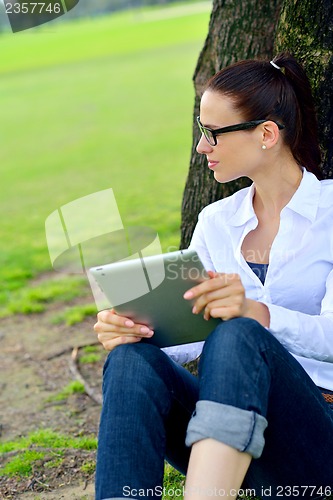 Image of Beautiful young woman with  tablet in park