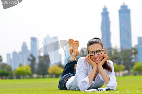 Image of Young woman reading a book in the park