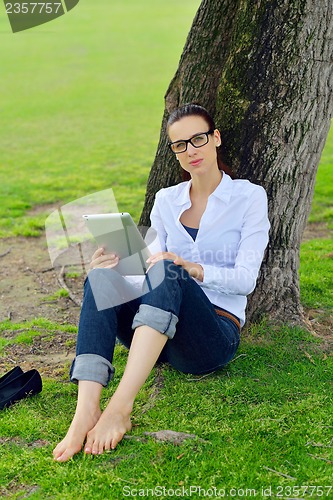 Image of Beautiful young woman with  tablet in park