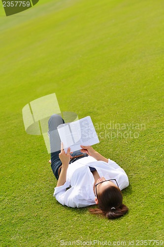 Image of Young woman reading a book in the park