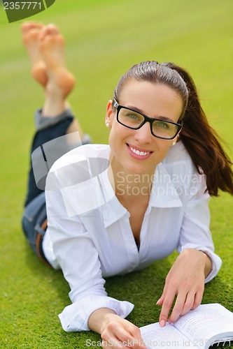 Image of Young woman reading a book in the park