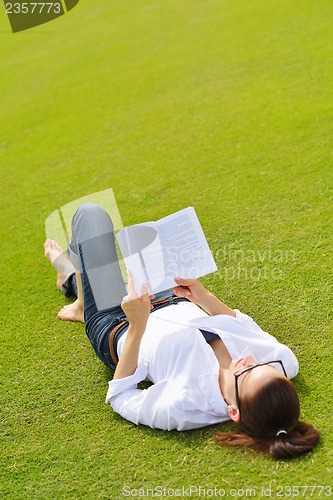 Image of Young woman reading a book in the park