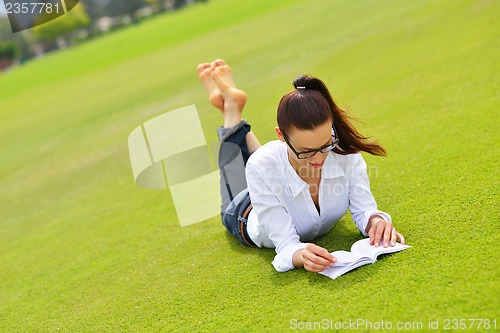 Image of Young woman reading a book in the park