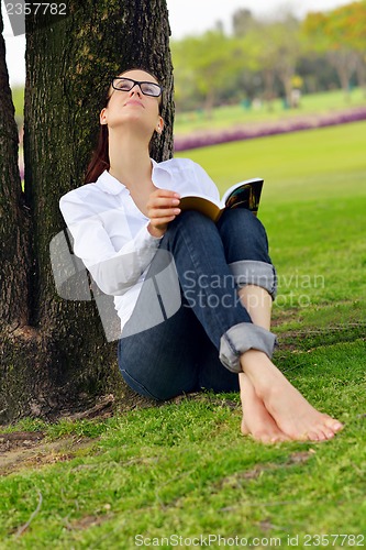 Image of Young woman reading a book in the park