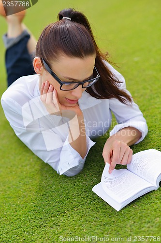 Image of Young woman reading a book in the park