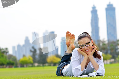 Image of Young woman reading a book in the park