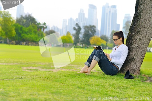 Image of Young woman reading a book in the park