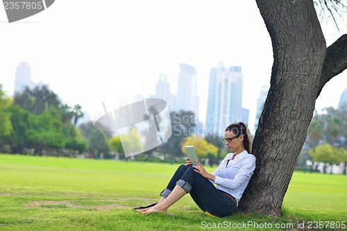 Image of Beautiful young woman with  tablet in park