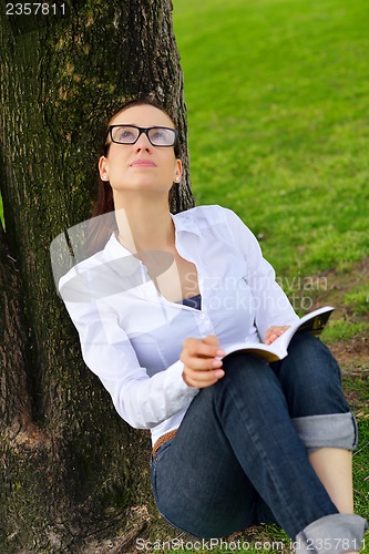 Image of Young woman reading a book in the park
