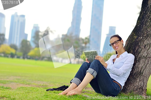 Image of Beautiful young woman with  tablet in park
