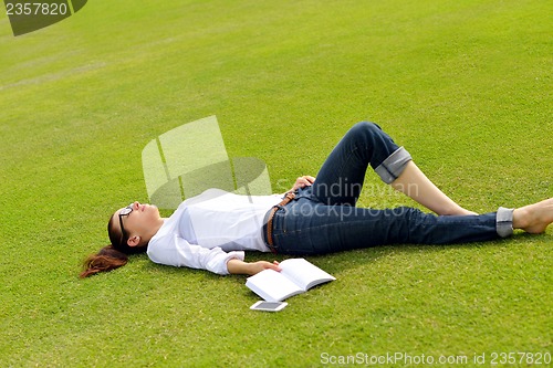 Image of Young woman reading a book in the park