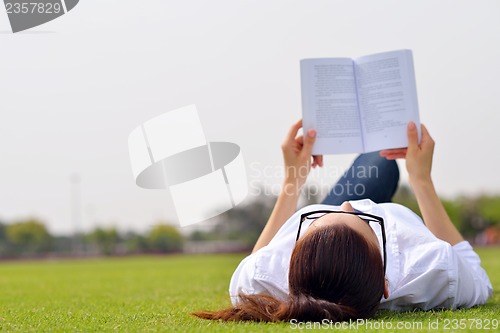 Image of Young woman reading a book in the park