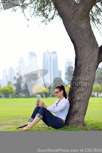 Image of Beautiful young woman with  tablet in park