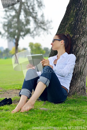 Image of Beautiful young woman with  tablet in park