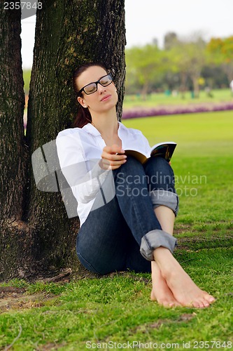 Image of Young woman reading a book in the park