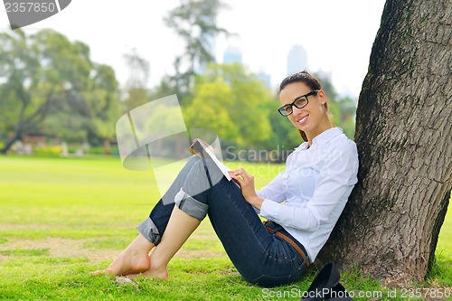 Image of Young woman reading a book in the park