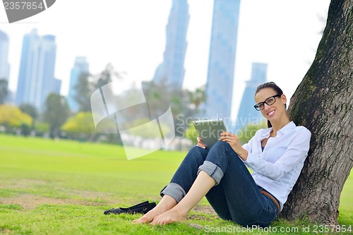 Image of Beautiful young woman with  tablet in park