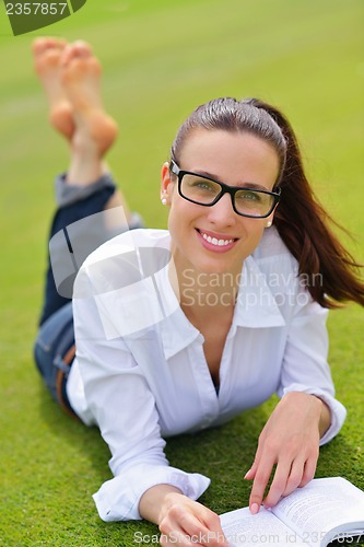 Image of Young woman reading a book in the park