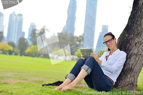 Image of Beautiful young woman with  tablet in park