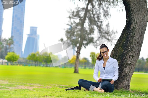 Image of Beautiful young woman with  tablet in park